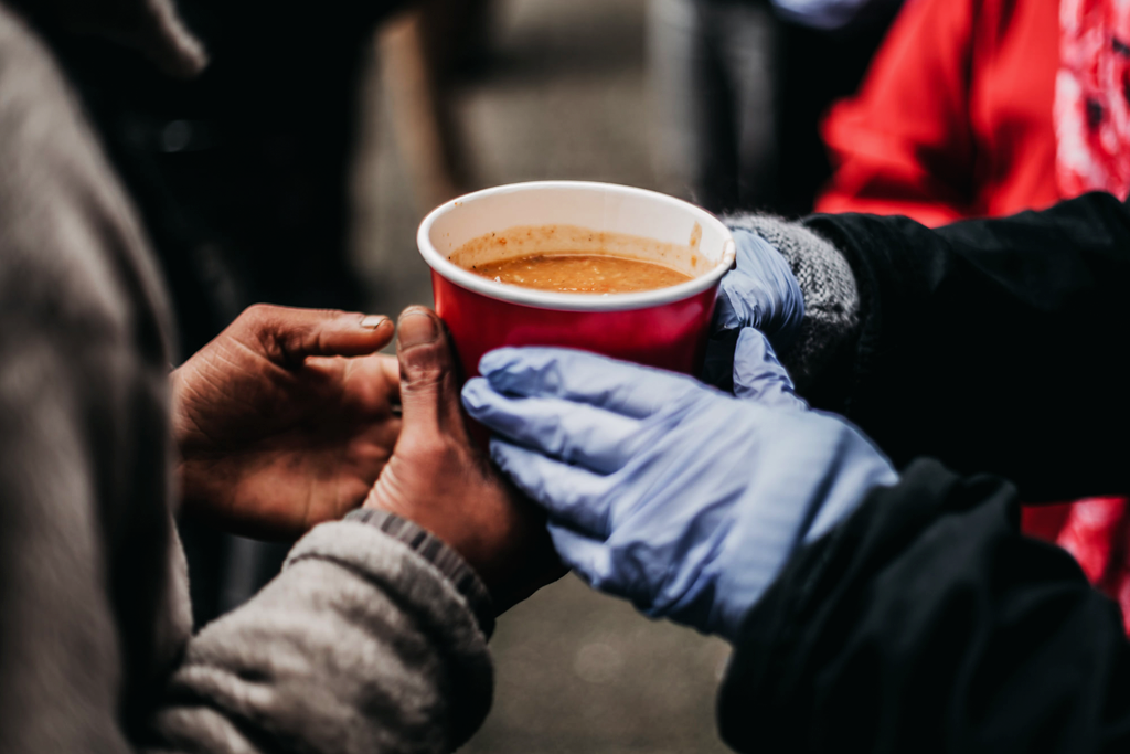 Ladles of Love volunteer handing out soup to a homeless person